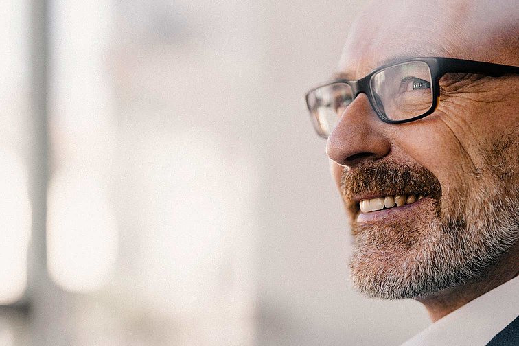 Mann mit Brille und grauem Bart lächelt